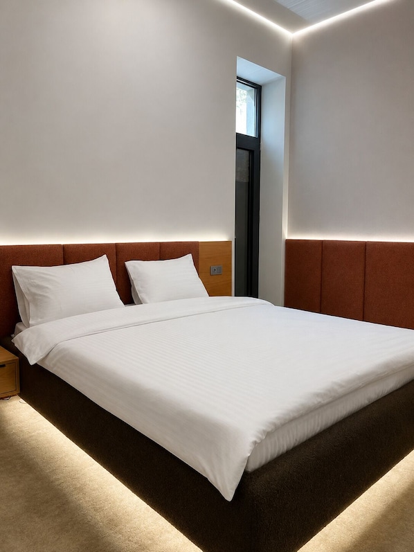 Ein modernes Hotelzimmer mit einem großen Bett, einem Nachttisch und einer fest installierten Kopfteil.
