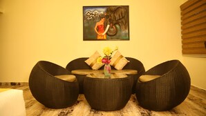 A room with wicker furniture, a glass table, and a painting on the wall. - District Gravity (Shamirpet)