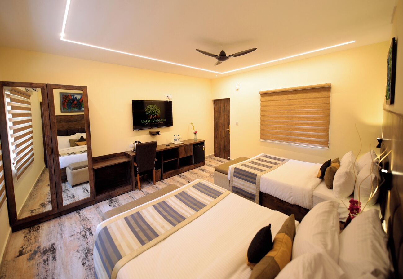 Una habitación de hotel con dos camas, un escritorio, un televisor y un ventilador de techo.