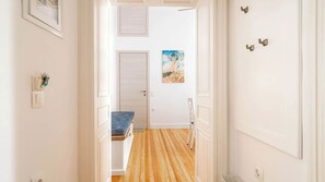 Ein Korridor mit Holzboden, weißen Wänden, einer Bank, einer Tür und einem Gemälde an der Wand.