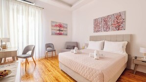 Ein Hotelzimmer mit einem Bett, zwei Stühlen, einem Schreibtisch und einem Bild an der Wand.