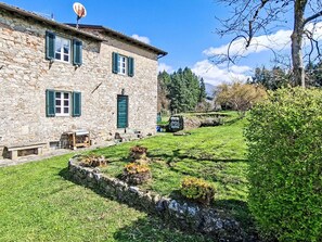 Un edificio in pietra con persiane verdi, un'antenna parabolica e un giardino murario in pietra.