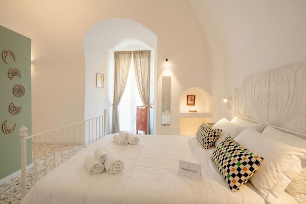 A hotel room with a bed, towels, a sign, and a view through an archway. - Auriga Elegance in Modugno (Modugno)