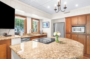 Eine Küche mit Granit Arbeitsplatten, Holzschränken, einem eingebauten Backofen und einem Kühlschrank.