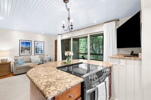 A modern kitchen with a granite countertop, stainless steel appliances, and a large window offering a view of greenery. - Beach access, close to West Beach conference (Kiawah Island)