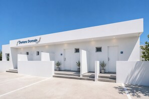 Un edificio moderno con un letrero que dice 'Dorians Domain'. Tiene un techo plano, una serie de escalones que conducen a la entrada y plantas en macetas en la base de los escalones.