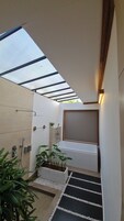 Un baño moderno con tragaluz, ducha, bañera y un pequeño jardín.