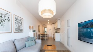Uma sala de estar moderna com sofá, televisão e área de jantar.
