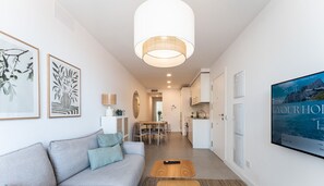 A modern living room with a sofa, a TV, and a dining area. - Fancy 2 Bedroom Fuengirola Escape REF071 (Fuengirola)