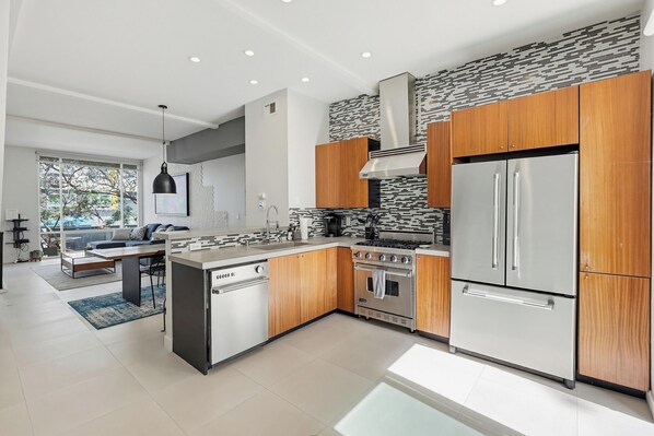 A modern kitchen with wooden cabinets, a stainless steel refrigerator, and a built-in oven.