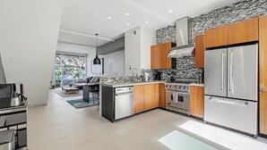 Una cocina moderna con electrodomésticos de acero inoxidable, armarios de madera y salpicadero de piedra.