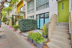 A row of modern buildings with a green door, concrete steps, and potted plants.