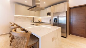 Una cocina moderna con una isla grande, electrodomésticos de acero inoxidable y una puerta de madera.