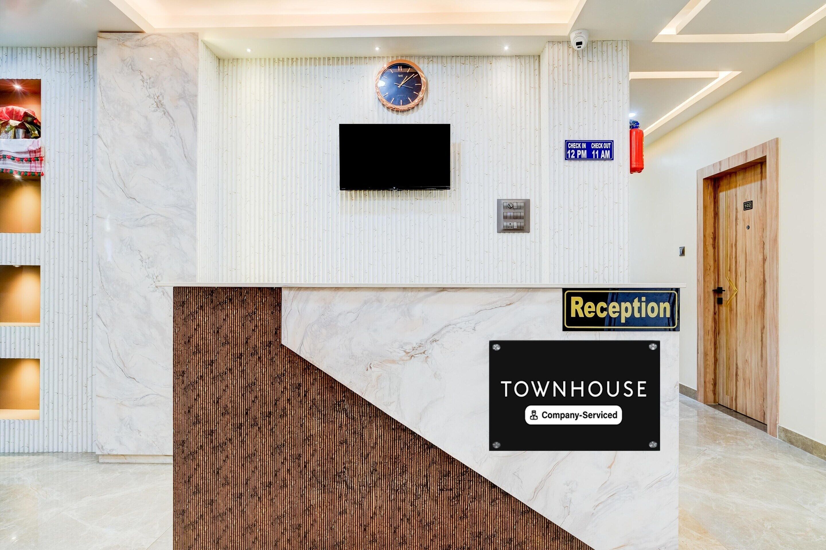 A reception desk with a clock, a sign indicating check-in times, and a 'Reception' label.