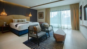 A modern hotel room with a large bed, two bedside tables, a sofa, a coffee table, and a large window with curtains. - Joannes (Abidjan)