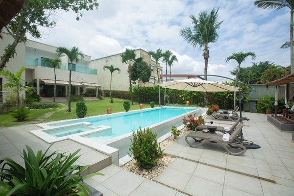 Una piscina al aire libre, sombrillas, sillones reclinables de piscina