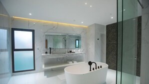 A modern bathroom with a freestanding bathtub, a large mirror, and marble walls. - Joannes (Abidjan)