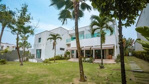 A modern two-story building with a well-maintained lawn and palm trees. - Joannes (Abidjan)