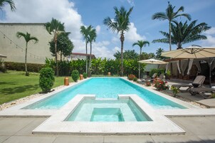 Una piscina al aire libre, sombrillas, sillones reclinables de piscina