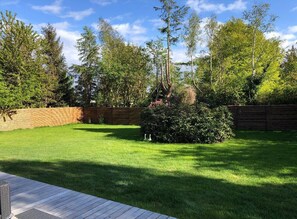 Ein gepflegter Garten mit einer Holzdiele, verschiedenen Bäumen und einem Holzzaun.