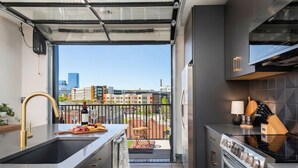 Uma cozinha moderna com uma janela grande, forno embutido e área de refeições com vista para a cidade.