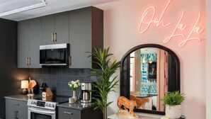 Cozinha moderna com micro-ondas, fogão e máquina de café, um espelho grande e um letreiro de neon.