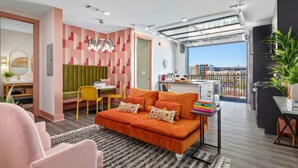 Uma sala de estar moderna com sofá, área de jantar e varanda com vista para a cidade.