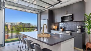 Cozinha moderna com uma ilha grande, banquetas, micro-ondas e vista para o exterior.