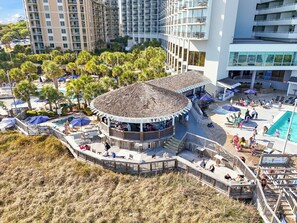 Ein Resort mit einem zentralen, kreisförmigen Gebäude, einem Poolbereich und einem Strand.