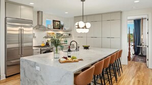 A modern kitchen with a marble island, stainless steel appliances, and a pendant light. - Luxury Retreat - Double Rooftop Deck Game Room (Nashville)