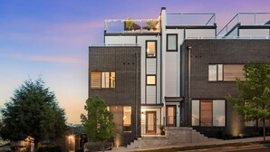 A modern two-story house with a brick facade, large windows, and a flat roof with solar panels. - Luxury Retreat - Double Rooftop Deck Game Room (Nashville)
