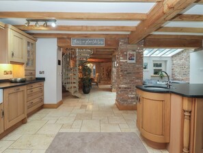 A kitchen with wooden cabinets, a black countertop, a spiral staircase, and a sign that reads 'there's no place like home.' - Mill Race Cottage (Driffield)