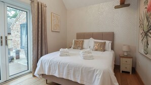 Een slaapkamer met een bed, nachtkastje, lamp, deur en raam.