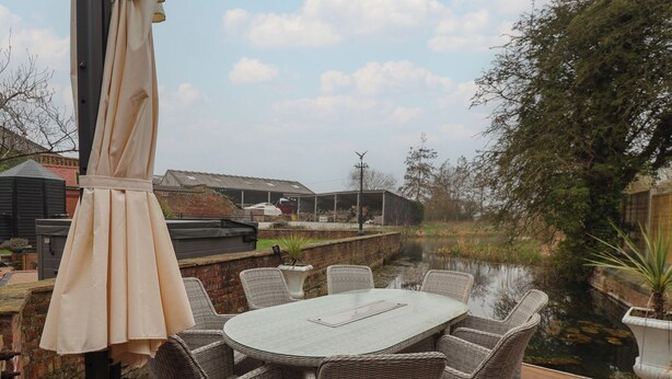 Een terras buiten met rieten meubels, een tafel en een parasol.