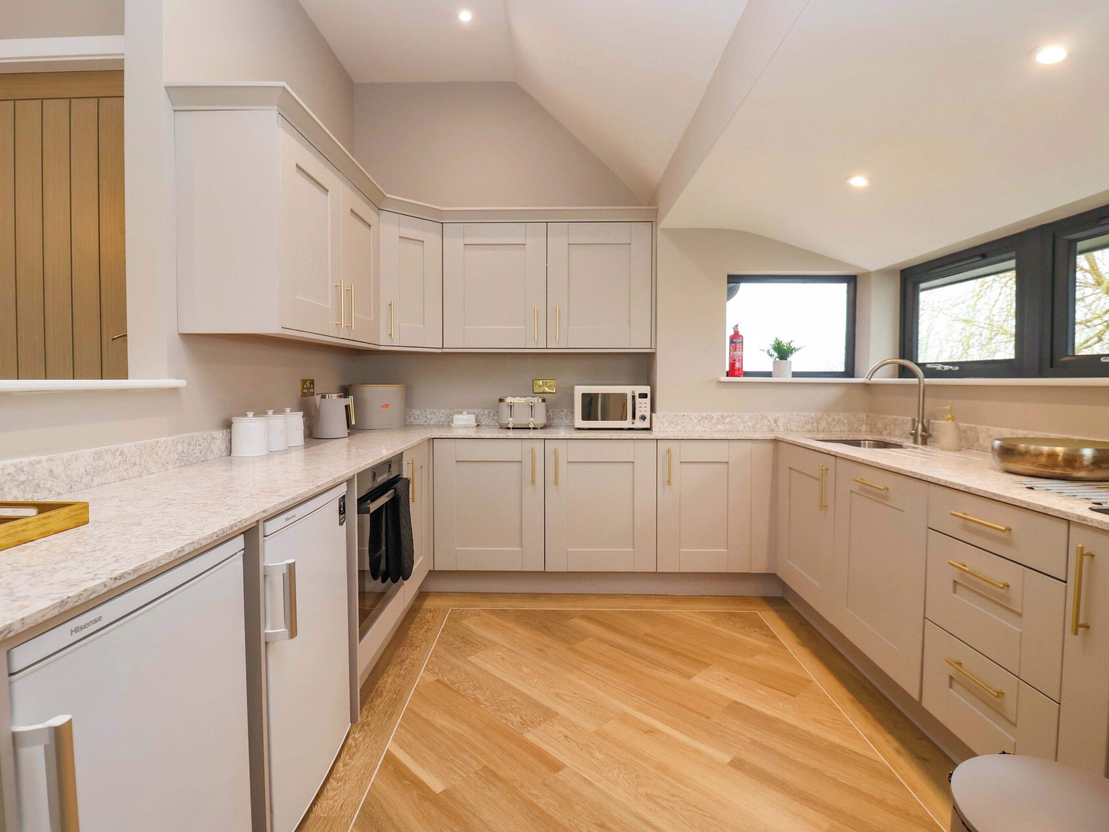 A modern kitchen with white cabinets, a microwave, and a sink.