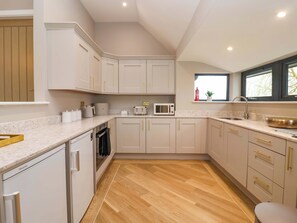 A modern kitchen with white cabinets, a microwave, and a sink. - Swing Bridge Cottage (Driffield)