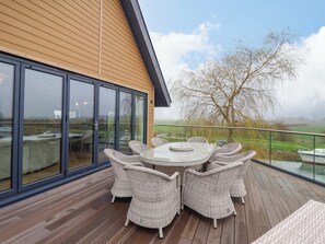 A deck with wicker furniture and a glass door leading to a view of a rural landscape. - Swing Bridge Cottage (Driffield)
