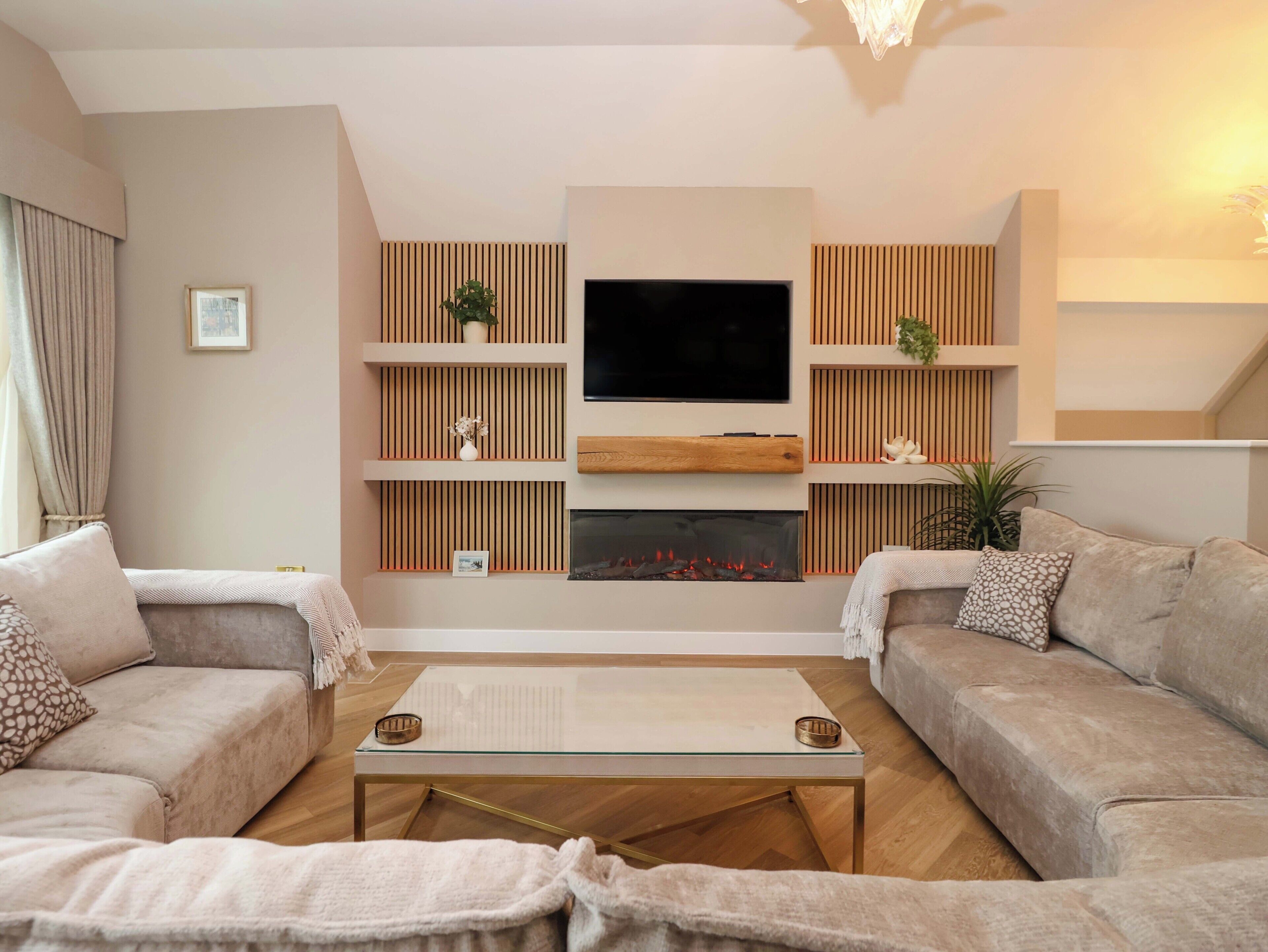 Ein modernes Wohnzimmer mit Flachbildfernseher, Holzregalen, einem Kamin und zwei Sofas.
