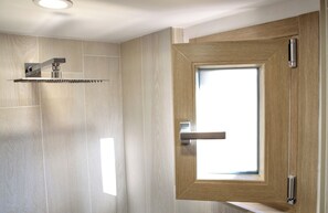 Ein modernes Badezimmer mit Dusche, einer Holztür und einem Fenster.