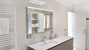 A modern bathroom with a white vanity, a large mirror, and a towel rack.