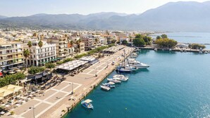Un pueblo costero con un puerto deportivo, edificios y montañas al fondo.