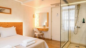 Una habitación de hotel con cama, escritorio, silla, ducha y espejo.