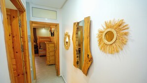 Un pasillo con puertas de madera, un espejo y un adorno en forma de sol en la pared.