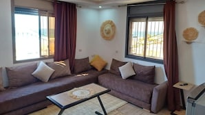 Una sala de estar con un sofá seccional, una mesa de centro y una lámpara de techo.