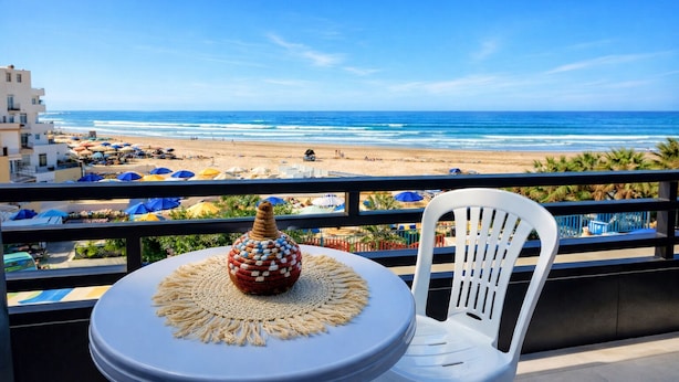Un balcón con vista a la playa, una cesta tejida y una silla blanca.