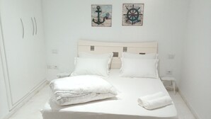 A white room with a bed, a black rug, and two wall art pieces. - Peaceful 1-bedroom apartment with AC in charming La Marsa (La Marsa)