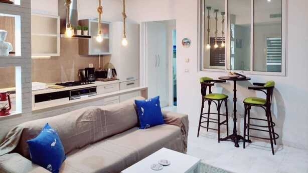 A modern kitchen with a dining area, a sofa with cushions, and a bar stool set. - Peaceful 1-bedroom apartment with AC in charming La Marsa (La Marsa)