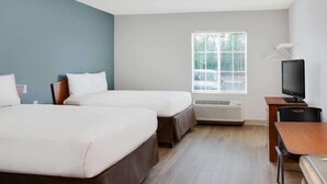 A hotel room with two beds, a TV, a desk, and a window with blinds. - Woodspring Suites Jacksonville East 295 Cruise Port (Jacksonville)