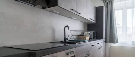 Una cocina moderna con horno empotrado, microondas y lavamanos.