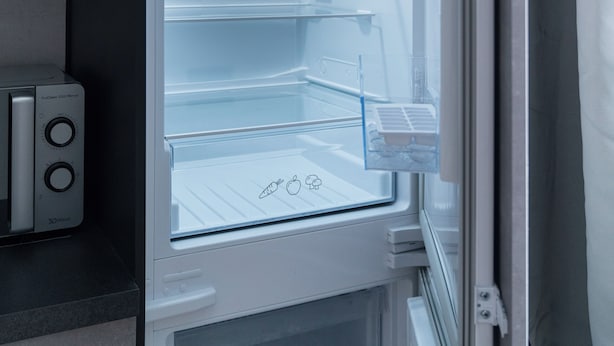 An open refrigerator with clear shelves and a control panel.